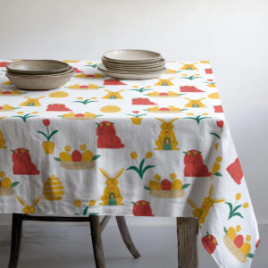 Obrus z detalem przy zastawie talerzy i misek, wzór z pisanek i króliczków przy krawędzi stołu