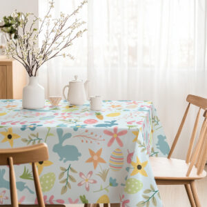 Stół z obrusem w jasnych kolorach ozdobiony wazonem i zastawą