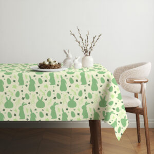 Stół udekorowany ceramiką i gałązkami, obrus z motywem wielkanocnym w zieleni