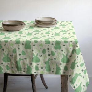 Widok stołu z talerzami na obrusie ozdobionym zającami i pisankami