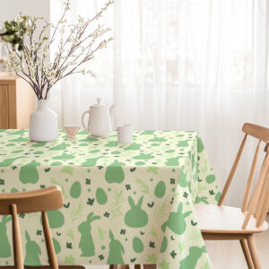 Jasna jadalnia z nakrytym stołem, obrus z zielonymi sylwetkami zajączków i roślinnymi wzorami