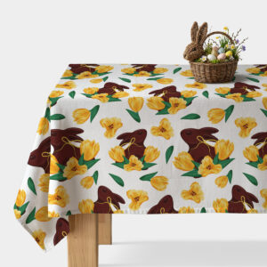 Obrus na stole z motywem czekoladowych zajączków i żółtych tulipanów z koszykiem wielkanocnym na rogu stołu