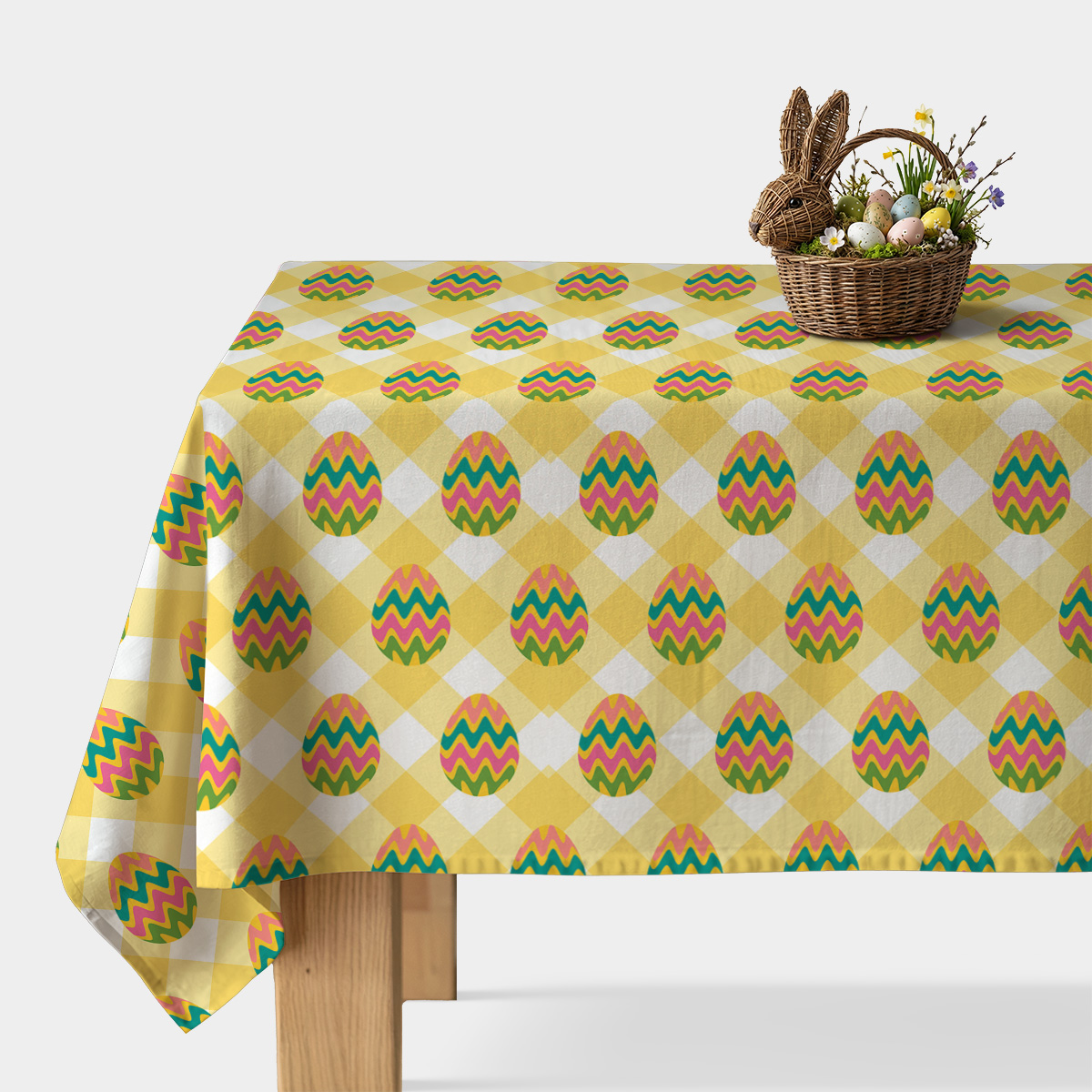 Obrus w żółtą kratę z kolorowymi pisankami na stole z koszykiem wielkanocnym