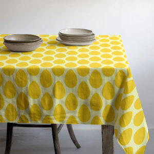 widok stołu z talerzami na obrusie w żółty wzór jajek