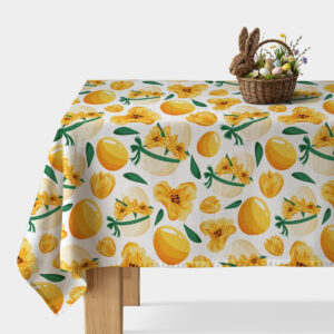 główne ujęcie stołu z obrusem w żółte pisanki i wiosenne kwiaty oraz wiklinowym koszykiem z dekoracyjnymi jajkami