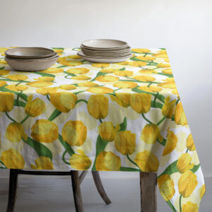 Stół nakryty obrusem w żółte tulipany z ułożonymi talerzami i miskami