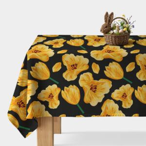 Obrus z dużymi żółtymi tulipanami na czarnym tle rozłożony na stole z wielkanocną dekoracją w wiklinowym koszyku