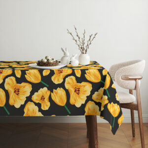 Aranżacja stołu z obrusem w żółte tulipany, białą porcelaną i dekoracyjnymi gałązkami w wazonie