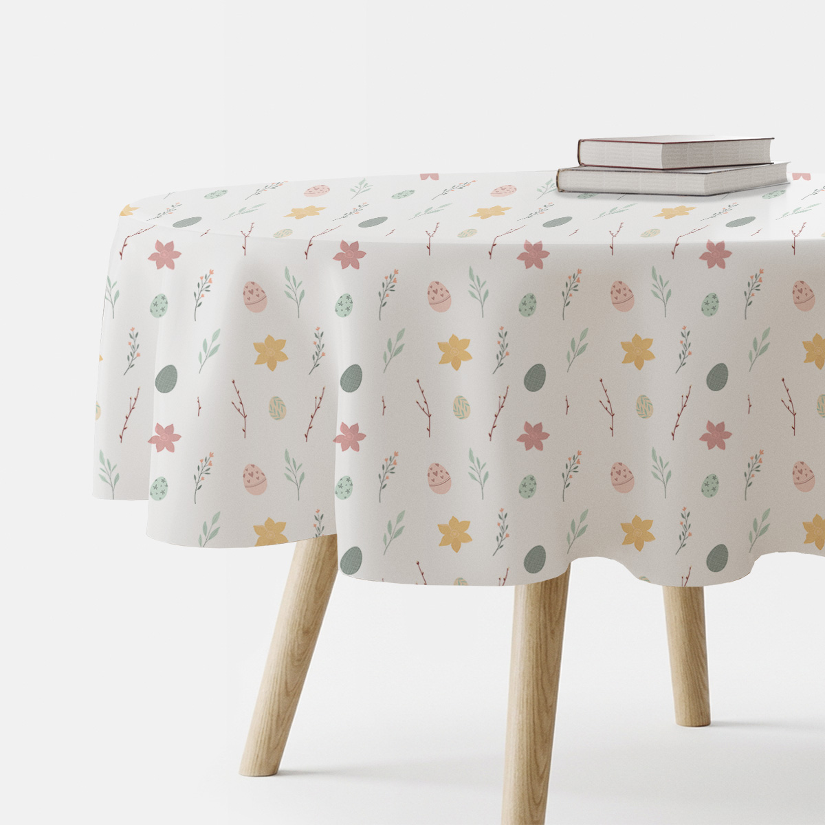 okrągły obrus w pastelowy wzór z pisankami i gałązkami na białym tle, ujęcie stołu z książkami
