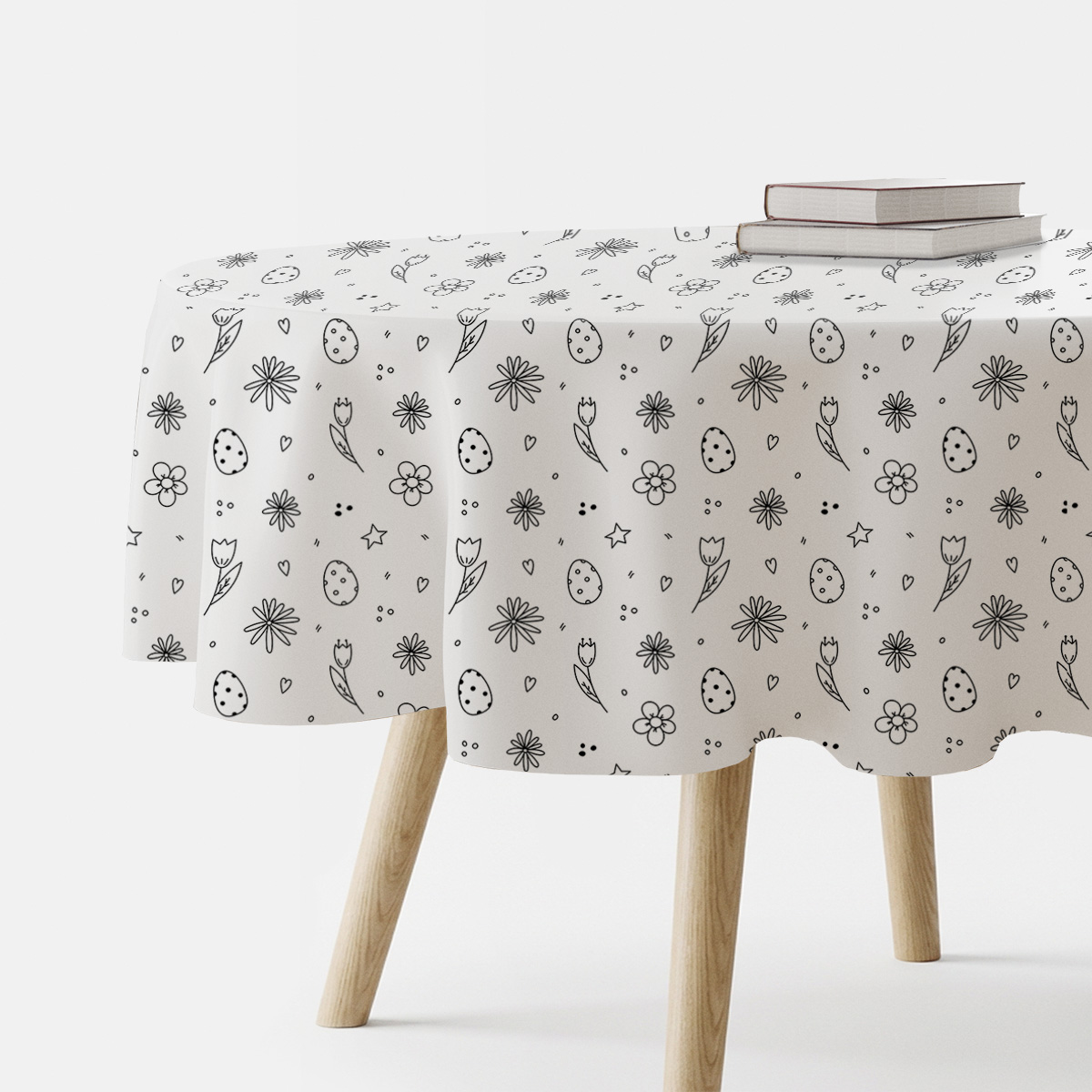 Okrągły obrus z czarno-białym wzorem pisanek i drobnych kwiatów na stole, widok z boku