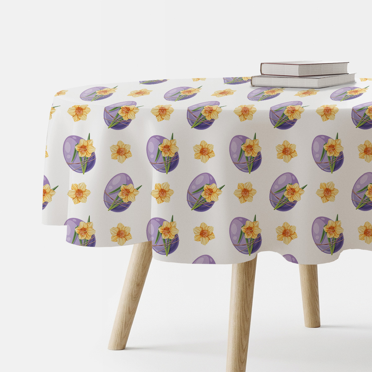 Okrągły obrus z motywem fioletowych pisanek i żółtych żonkili na stole w aranżacji z książkami