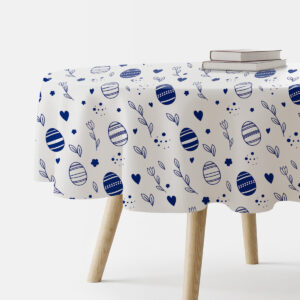 Okrągły biały obrus z granatowymi pisankami i gałązkami na stole, widok boczny