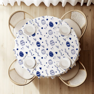 Widok z góry na okrągły stół udekorowany obrusem z granatowymi pisankami i ustawionymi talerzami