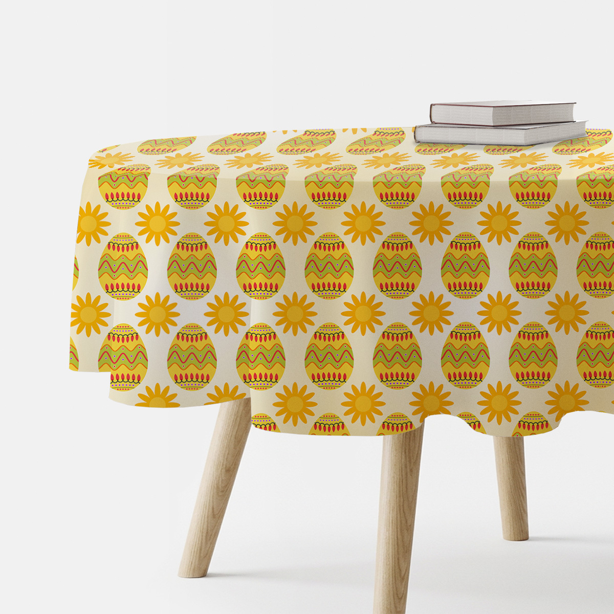 okrągły obrus z motywem wielkanocnych pisanek i słoneczek na stole, z dwoma książkami u krawędzi