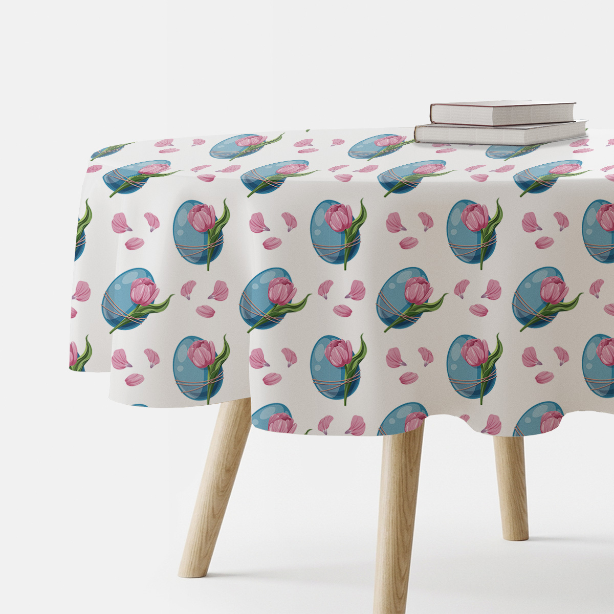 okrągły obrus z motywem niebieskich pisanek i różowych tulipanów na stole z książkami