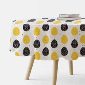 Okrągły obrus z wzorem żółtych i czarnych pisanek na białym tle, ujęcie z boku na stół z książkami