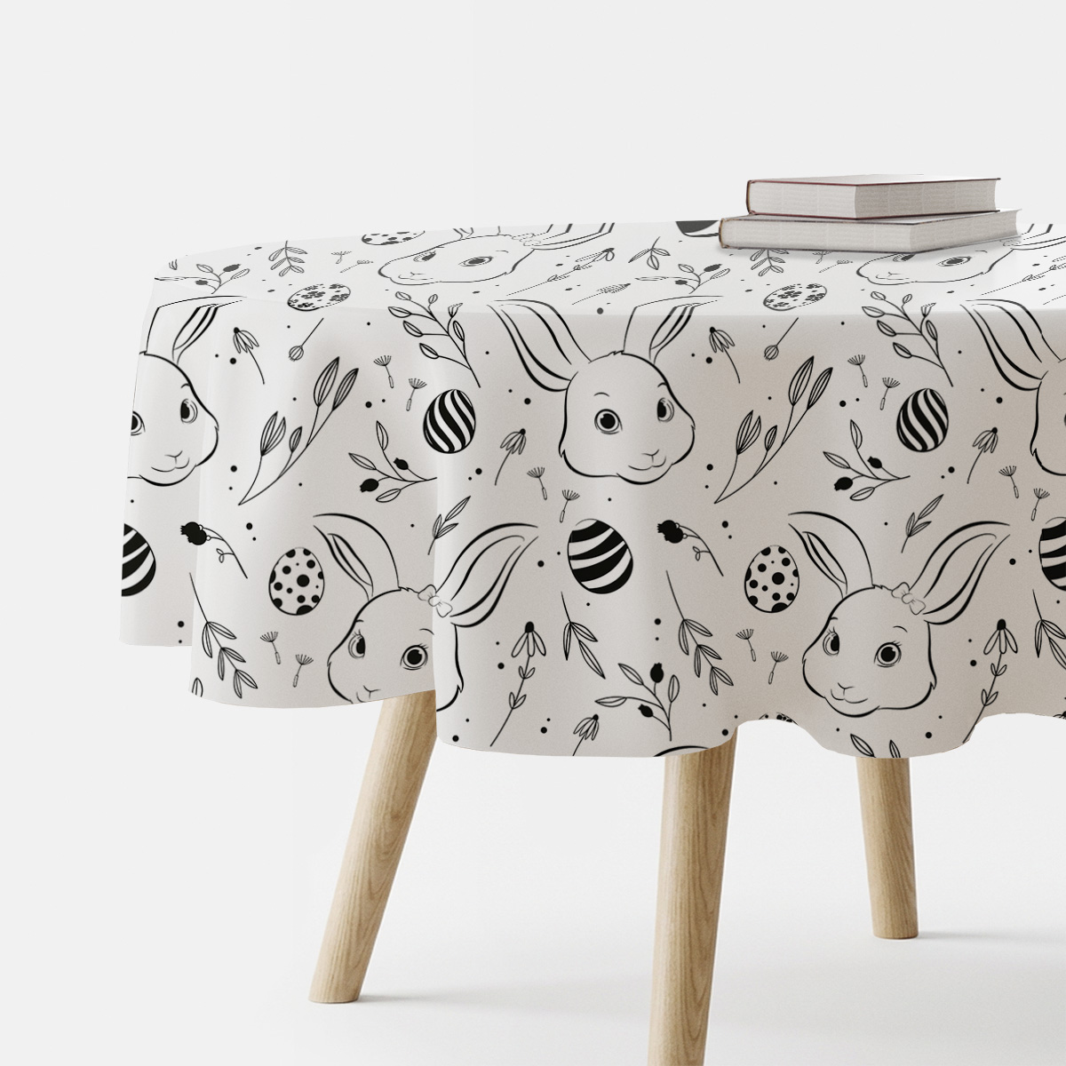 okrągły obrus z motywem króliczków i pisanek na stole widziany z boku z książkami na blacie