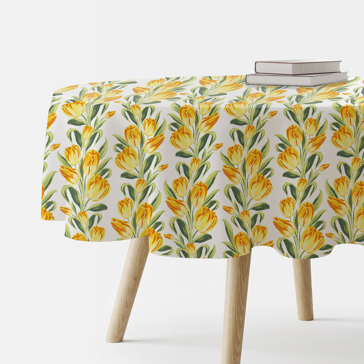 okrągły obrus z żółtymi tulipanami na białym tle na stole, widok z boku z książkami na krawędzi