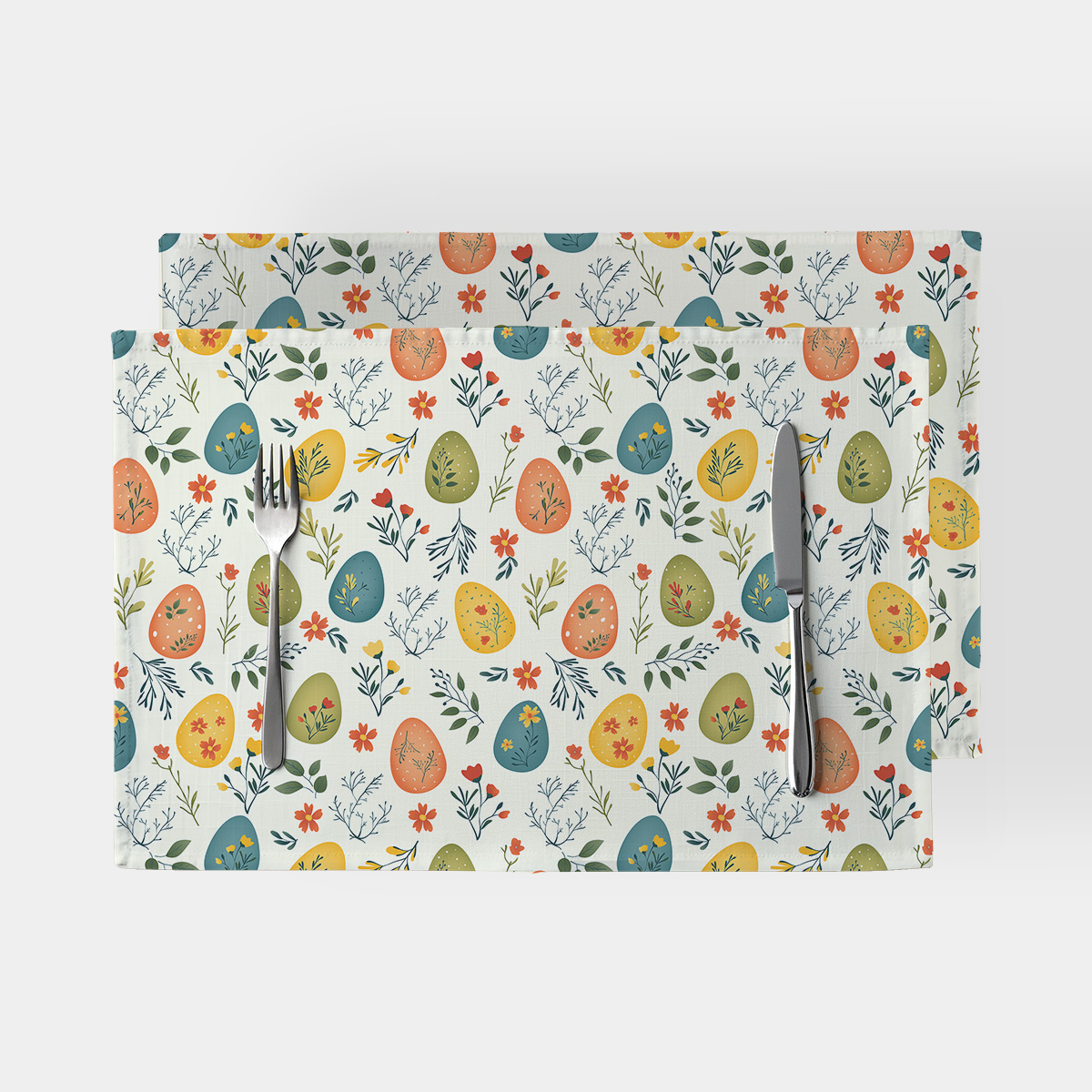 Zestaw dwóch podkładek na stół z motywem pastelowych pisanek i gałązek, ujęcie z góry pokazujące całe nakrycie