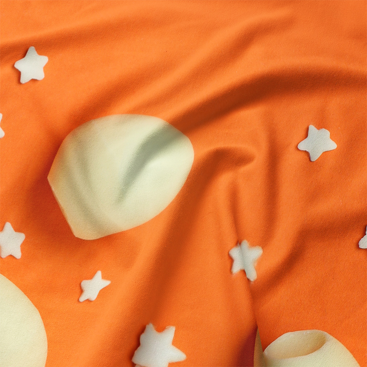 Zbliżenie na tkaninę i nadruk: kremowa pisanka oraz drobne białe gwiazdki