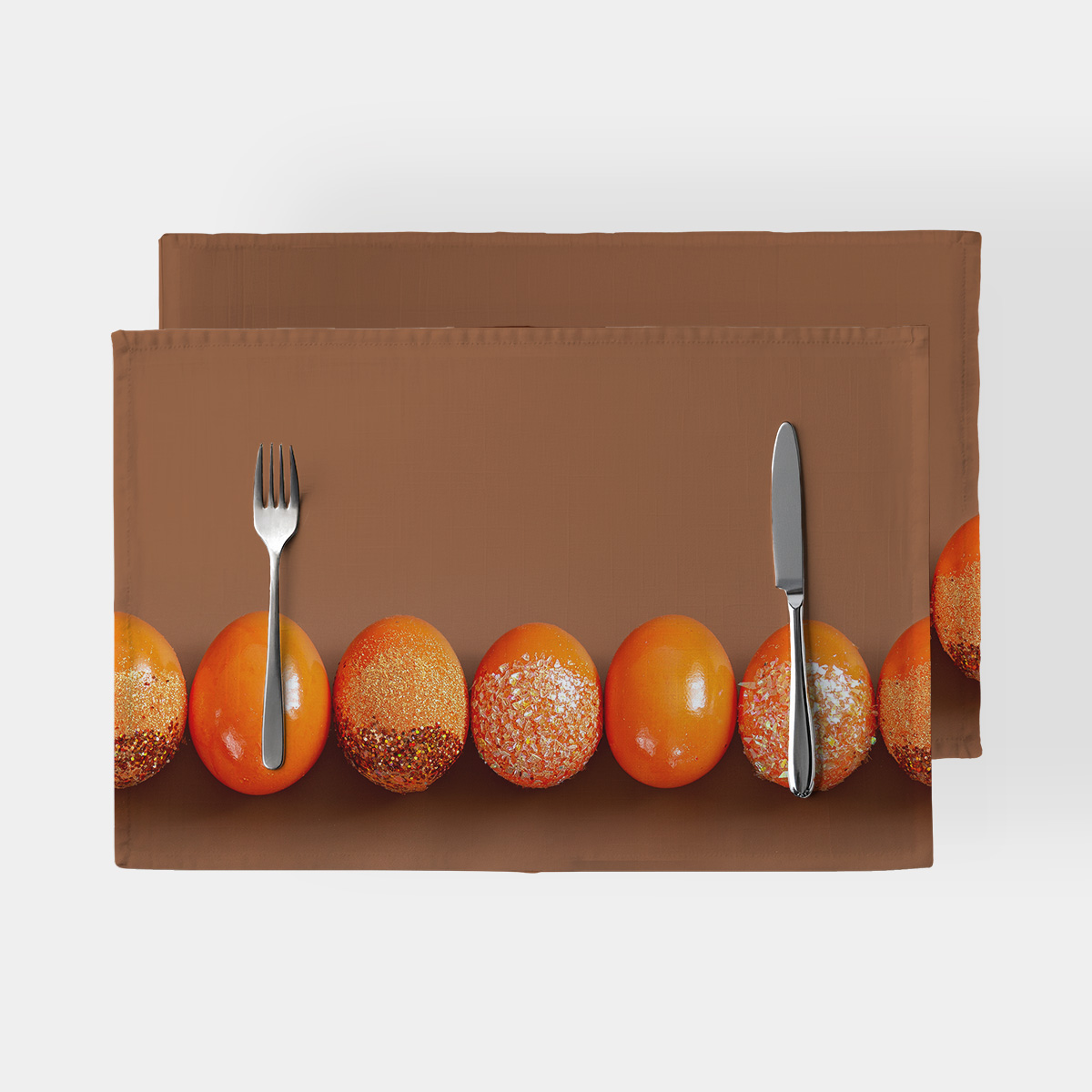 podkładka ze szeregiem pomarańczowych pisanek na brązowym tle, ujęcie od góry