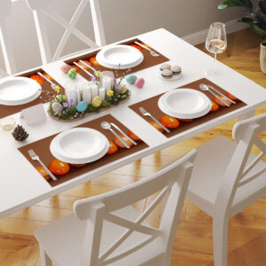 stół nakryty wieloma podkładkami z pomarańczowymi pisankami w rzędzie