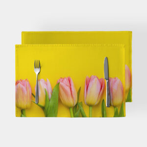 Podkładka z różowymi tulipanami na żółtym tle, ujęcie z góry z widocznymi sztućcami