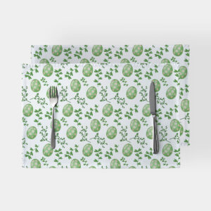 Dwie podkładki ułożone jedna na drugiej z motywem zielonych pisanek i gałązek, widok z góry ze sztućcami