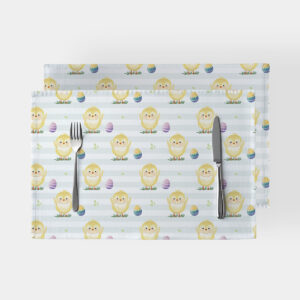 Widok z góry dwóch podkładek na stół z wzorem uśmiechniętych kurczaczków i pisanek na jasnym, paskowanym tle