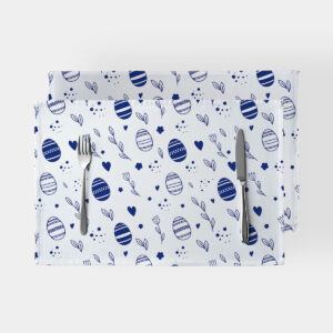 Dwie prostokątne podkładki na białym tle z granatowym motywem pisanek i gałązek, ułożone ze sztućcami