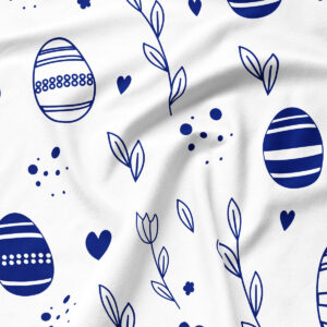 Zbliżenie na biały materiał z nadrukiem granatowych pisanek, gałązek i drobnych kropek