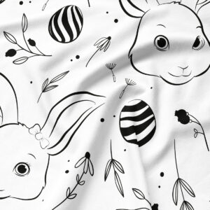 Zbliżenie na czarno-biały nadruk z króliczką, pisanką i delikatnymi listkami, widoczna faktura tkaniny