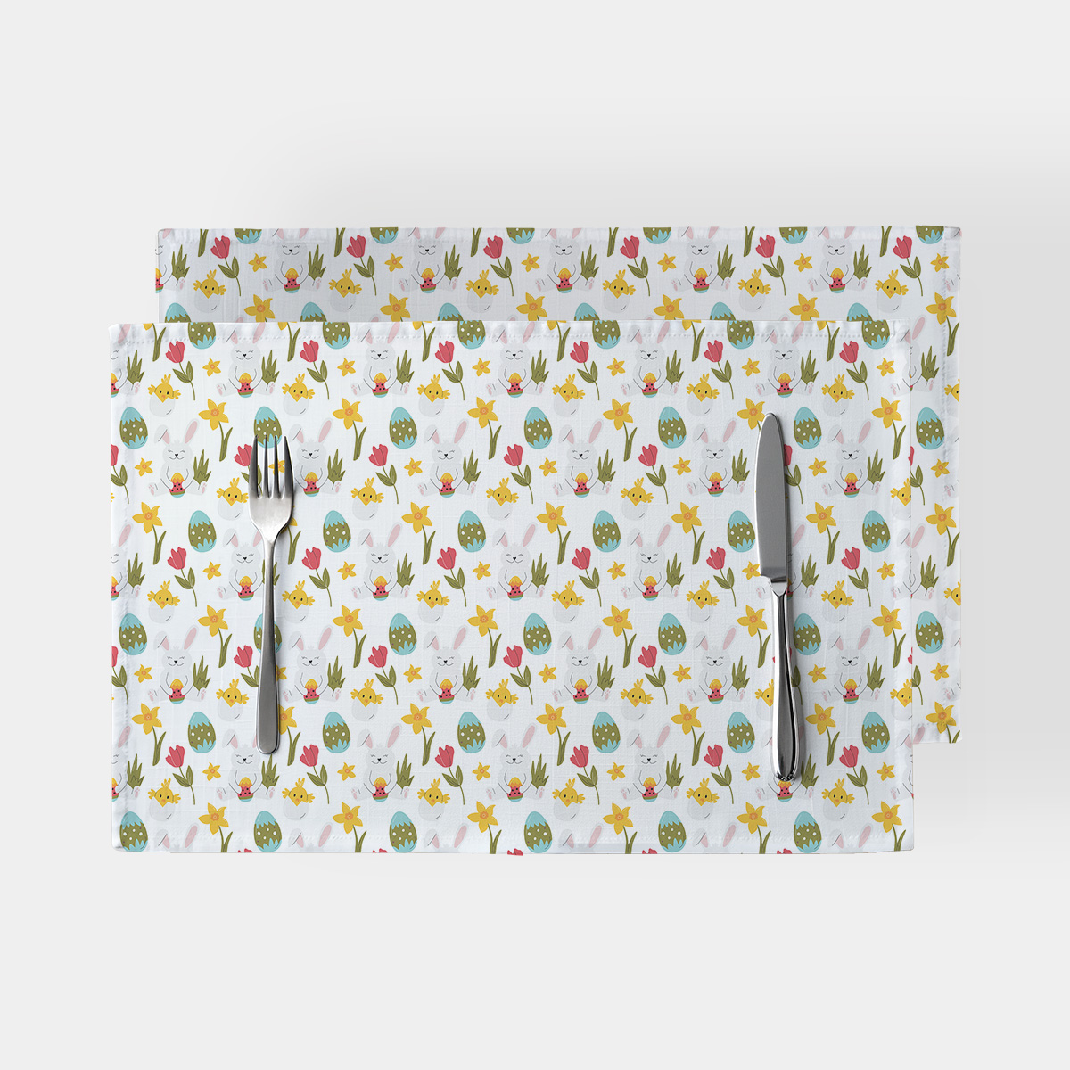 Para podkładek na stole z widocznym wielkanocnym wzorem z zajączkami, pisankami i kwiatami