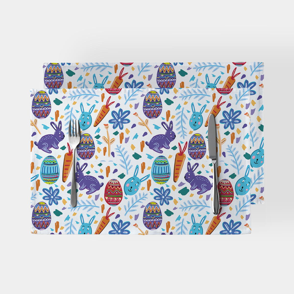 Para podkładek na stół z wesołym wielkanocnym wzorem z zajączkami i pisankami, widok z góry z sztućcami