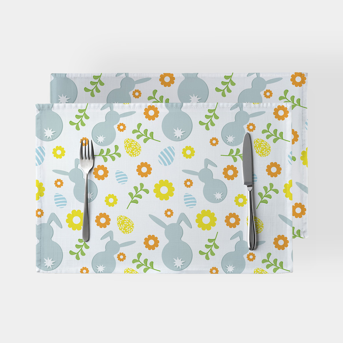 Główne ujęcie zestawu dwóch podkładek z motywem zajączków, pisanek i kwiatów na jasnym tle