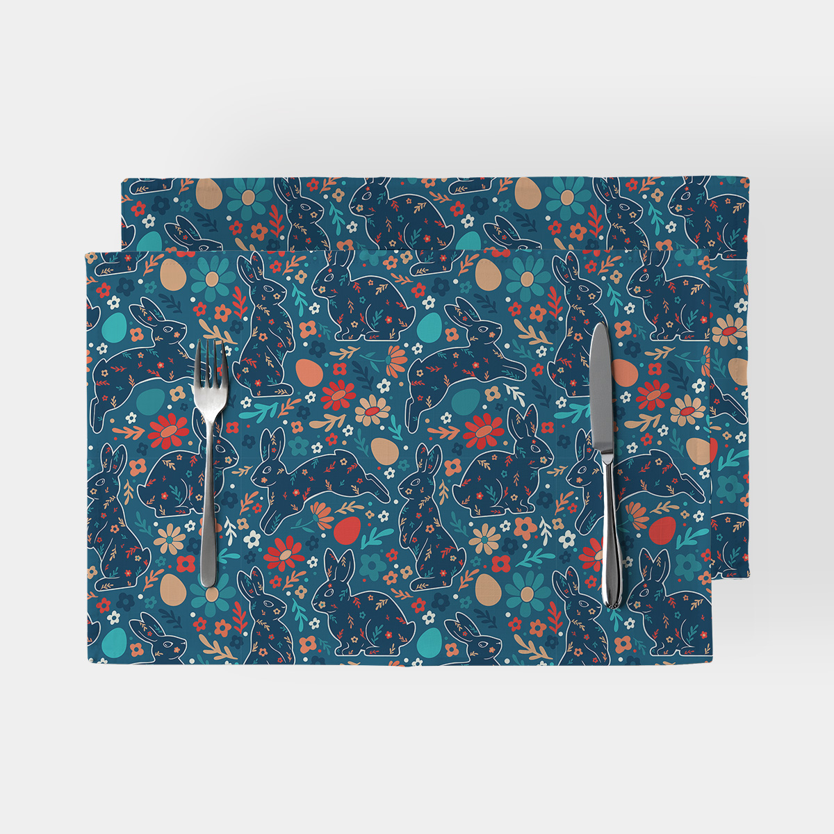 Dwie podkładki na stół z motywem wielkanocnych zajączków i kwiatów widok z góry z widelcem i nożem