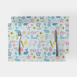 Dwie podkładki na stole z pastelowym wzorem zajączków, pisanek i kwiatów widziane z góry