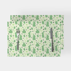 Dwie podkładki na stole z zielonym wzorem zajączków i sztućcami ułożonymi na jednej z nich
