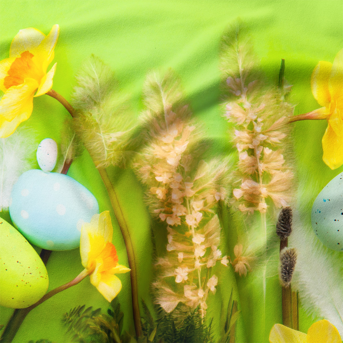 Zbliżenie na detal nadruku: żonkile, pastelowe jajka i delikatne trawy na zielonym tle