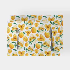 Dwie podkładki na stół z motywem żółtych pisanek i wiosennych kwiatów na białym tle ze sztućcami