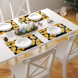 Stół nakryty kilkoma podkładkami z żółtymi tulipanami, talerzami i dekoracjami wielkanocnymi