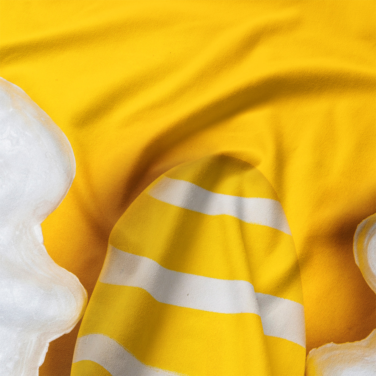 Zbliżenie na fakturę materiału i biało-żółtą pisankę