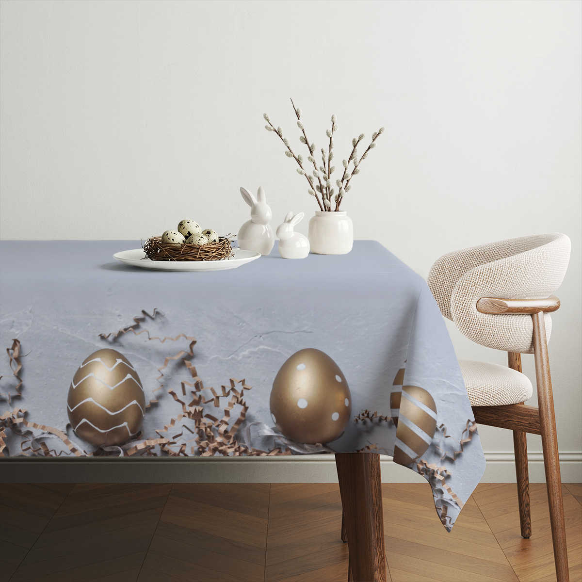 aranżacja stołu z obrusem, talerzem z gniazdem jajek i wiosenną dekoracją na tle neutralnego wnętrza