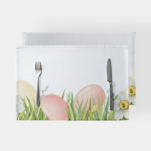 biała podkładka z motywem pastelowych pisanek w trawie ułożona z widocznymi sztućcami