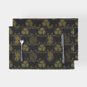 Czarne podkładki ze wzorem złotych pisanek i delikatnych gałązek, widok z góry na nakrycie stołu