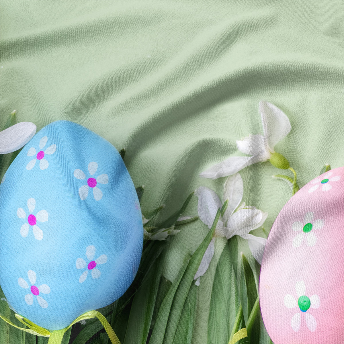 zbliżenie na niebieskie i różowe pisanki oraz białe kwiaty na miętowym tle podkładki