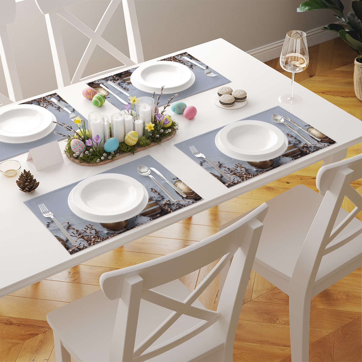Stół nakryty kilkoma podkładkami z motywem złotych pisanek, białe talerze i sztućce