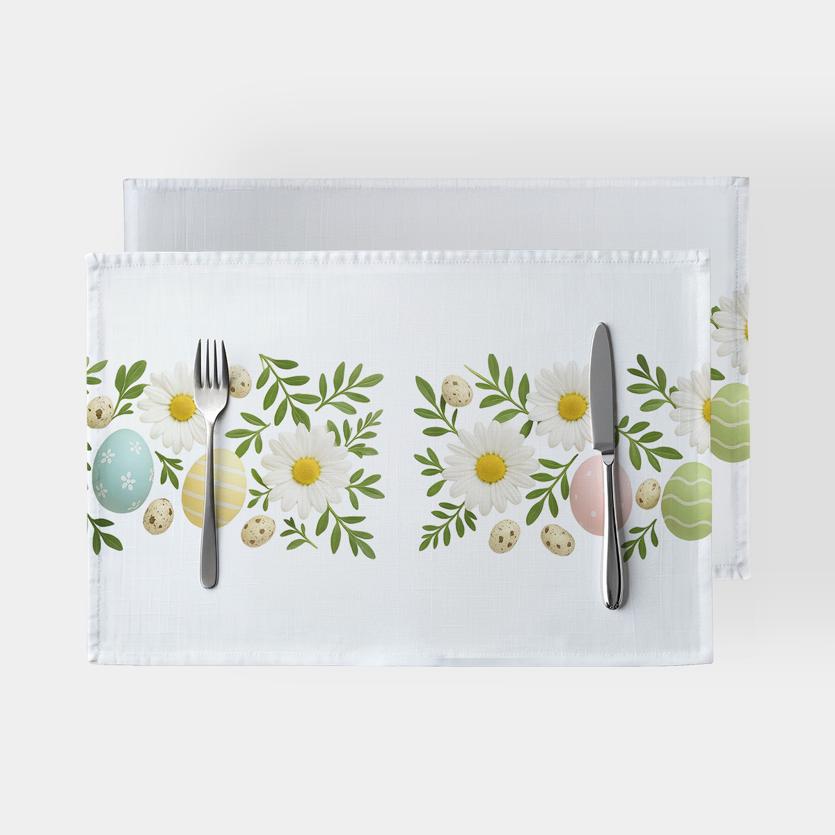 biała podkładka z motywem stokrotek i pastelowych pisanek na stole