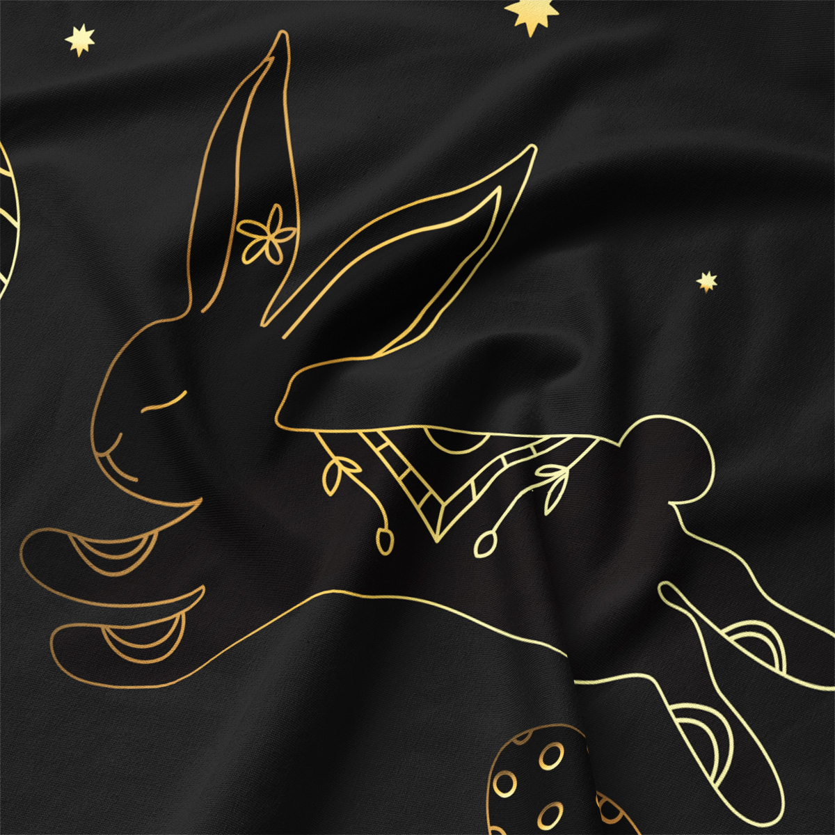 Zbliżenie na złoty kontur zajączka na czarnej tkaninie z widoczną fakturą materiału