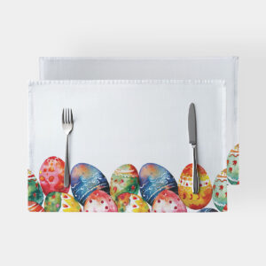 biała podkładka z akwarelowymi pisankami przy dolnej krawędzi, widok z góry z nożem i widelcem